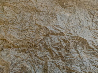A full-frame, overhead shot of brown crumpled paper with a richly textured surfaces.