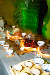 Traditional tea ceremony with clay teapot, cups and herbal tea on wooden table, authentic Asian cultural ritual