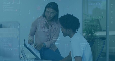 Pointing woman and man in business attire reviewing code at work desk, with monitor keyboard mouse