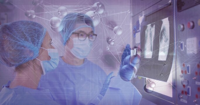 Pointing surgeon and assistant wearing scrubs at console in hospital lab, with molecular overlay