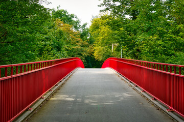 Eine gebogene Brücke mit roten Geländern über eine Strasse in Karlsruhe, Baden-Wuerttemberg,...