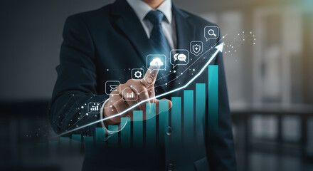 Businessman pointing to a rising financial graph with business icons on a digital interface