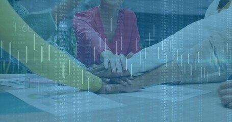 Stacking team hands over conference table in meeting room, with printed charts and digital overlay