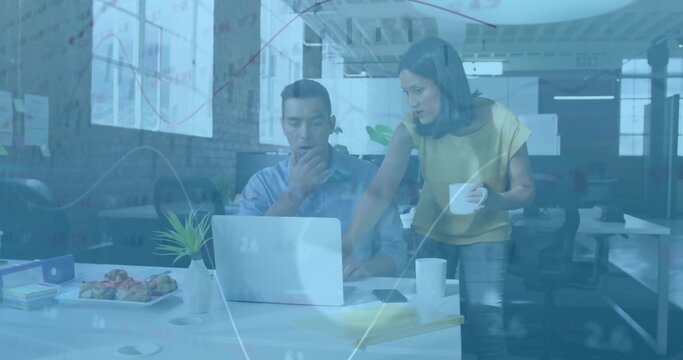 Collaborating coworkers viewing financial charts overlay on laptop at office desk with coffee mugs