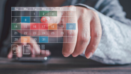A person's finger points to the 10th on a digital calendar overlay on a smartphone. This signifies scheduling an appointment or managing tasks on a wooden desk.