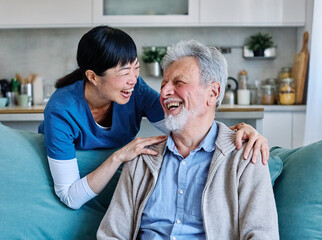 Doctor or nurse caregiver with senior man talking and having fun at home or nursing home