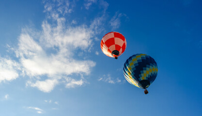 Two hot air balloons fly into the sky. Hot air balloon flight in the clouds. Red and Blue hot air balloons on a Sunny Day