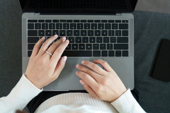 Focus. Young woman typing on a laptop from an overhead view.