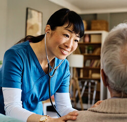 Doctor or nurse caregiver with senior man at home or nursing home using a stethoscope during an exam