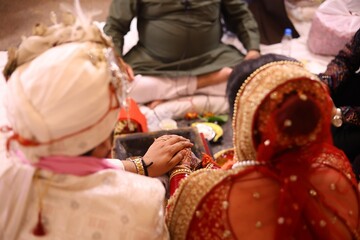Bride and Groom Holding Hands During Hindu Wedding Ritual with Priest