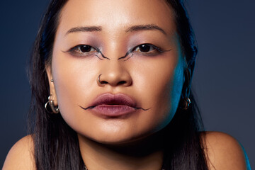Mystical allure of a young woman in creative makeup against a dark blue backdrop