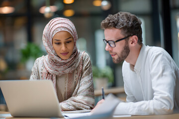Diverse business colleagues working together on a laptop in a modern office