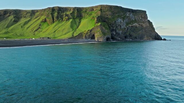 Aerial drone footage of Reynisfjara black sand beach Iceland. Reynisdrangar sea stacks rise from the Atlantic ocean against volcanic cliffs in cinematic 4K ProRes.