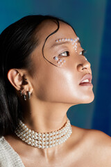 Creative makeup artistry on young woman with pearl accents in studio setting