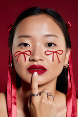 Creative makeup art showcases bows on a young woman's cheeks in a studio