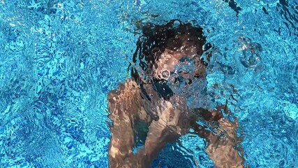 Little girl Child swimmer dives into the pool wearing outdoor swimming goggles. Child learning to swim.