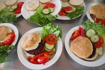 Handmade vegan burgers with fresh vegetables and salad on plates 