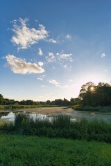 Sunset over a serene river with lush vegetation and clear blue skies in a peaceful rural setting