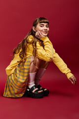 Young beautiful female student poses confidently in stylish outfit on vibrant backdrop