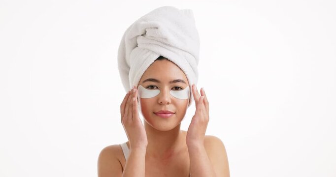 Woman, face and skincare with eye patches in studio for collagen on a white background. Portrait, female person or model with towel, beauty mask or facial cosmetics for anti aging on mockup space