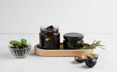 Two glass jars with sun dried plums on white table, copy space