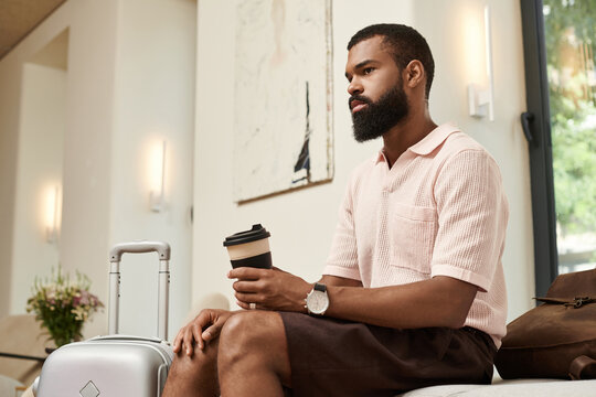 Charming African American man enjoys coffee in a modern hotel lobby setting