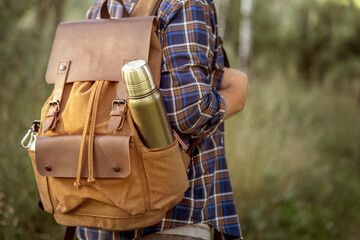 A man with a backpack and a thermos on a walk in the forest