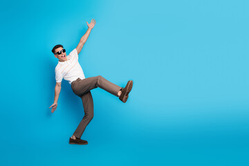 Obraz premium Stylish young man in casual fashion posing playfully against a bright blue background, showcasing vibrant energy and fun personality.