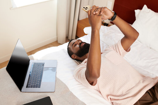 Relaxing in a modern hotel room, an African American man enjoys his vacation time