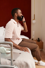 Fototapeta premium Relaxed black man enjoying a call in a modern hotel room while on vacation