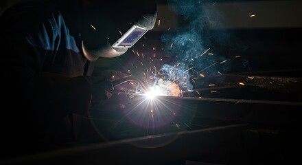 Welder Working with Protective Mask and Hot Sparks in Dark Workshop