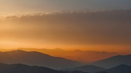 Obraz premium Sunset Over Mountain Range with Vibrant Orange and Blue Sky