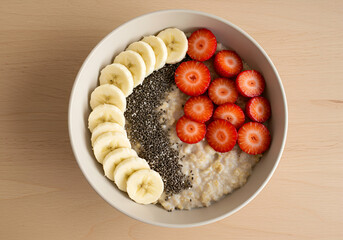 Healthy Lifestyle Breakfast Bowl with Oatmeal, Banana, Strawberries, and Chia Seeds in Overhead View