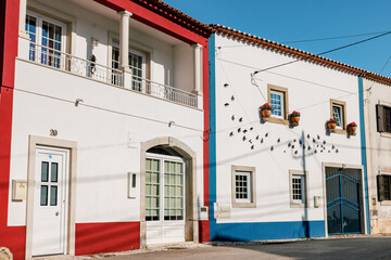 Fototapeta premium View of a traditional Portuguese house in a village near Óbidos, Portugal, showing whitewashed walls, blue trim, ceramic bird decorations and authentic rural architecture.