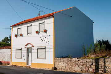 Scenic street view of white and blue traditional houses in an Óbidos village, Portugal, showing tiled roofs, ceramic birds and the charm of rural Portuguese architecture.