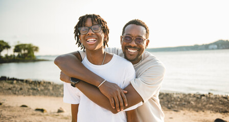 Cheerful black american father and is son against beautiful seascape