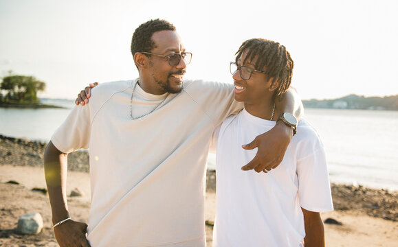 Cheerful black american father and is son against beautiful seascape