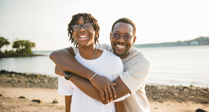 Cheerful black american father and is son against beautiful seascape