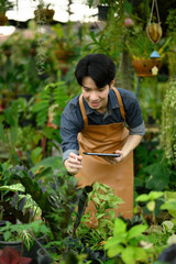 Botanist using tablet to study plant growth inside a lush greenhouse