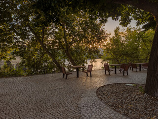 In Mirandela, Portugal, the riverside square by the Tua features outdoor tables and chairs for relaxation, framed by scenic bridges, gardens, and the charm of this northern town.