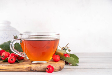 Fragrant autumn hawthorn berry tea. Herbal organic hot drink made from wild forest hawthorn berries, on white wooden background