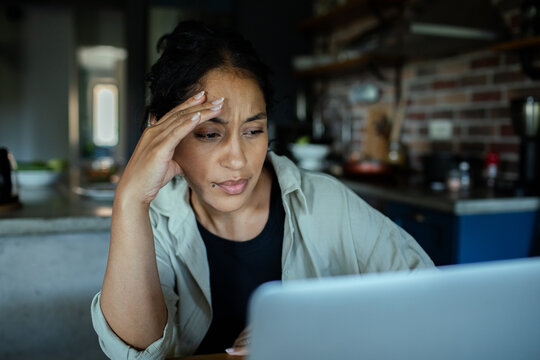 Woman looking stressed while working on laptop