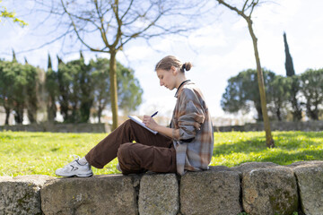 Fototapeta premium Young artist drawing outdoors in a park: finding inspiration in nature