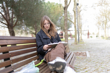 Obraz premium Young woman reading book on park bench