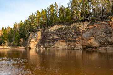  landscape with sandstone cliffs on the banks of the river Gauja, beautiful reflections in the water, the bank is covered with spruce forest, Erglu cliffs, Cesu municipality, Latvia
