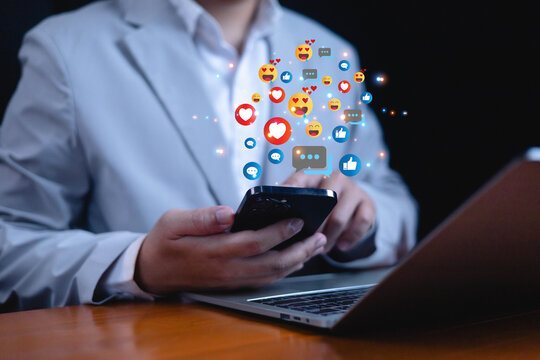 Close up of man using smartphone with colorful social media icons, likes, comments, and emojis floating above, symbolizing online communication, digital marketing, and social interaction.