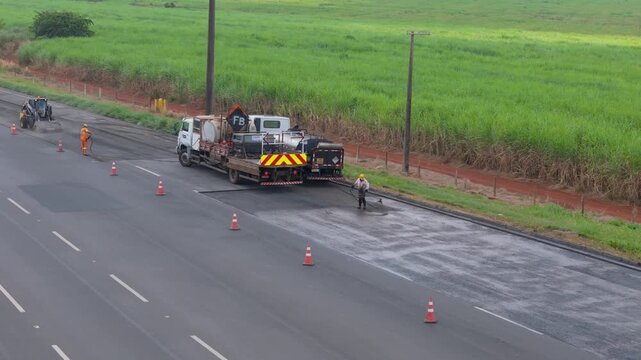 Workers Operating Machinery Applying Asphalt on Road Construction