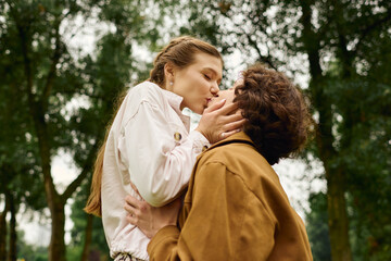Fototapeta premium Loving couple shares a tender kiss during a romantic walk in a serene park setting