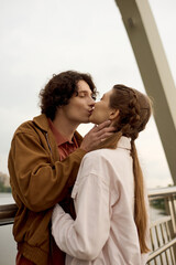 Young couple shares a romantic moment while walking along a scenic bridge in the park
