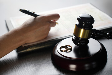 Signing divorce papers with wedding rings and judge gavel